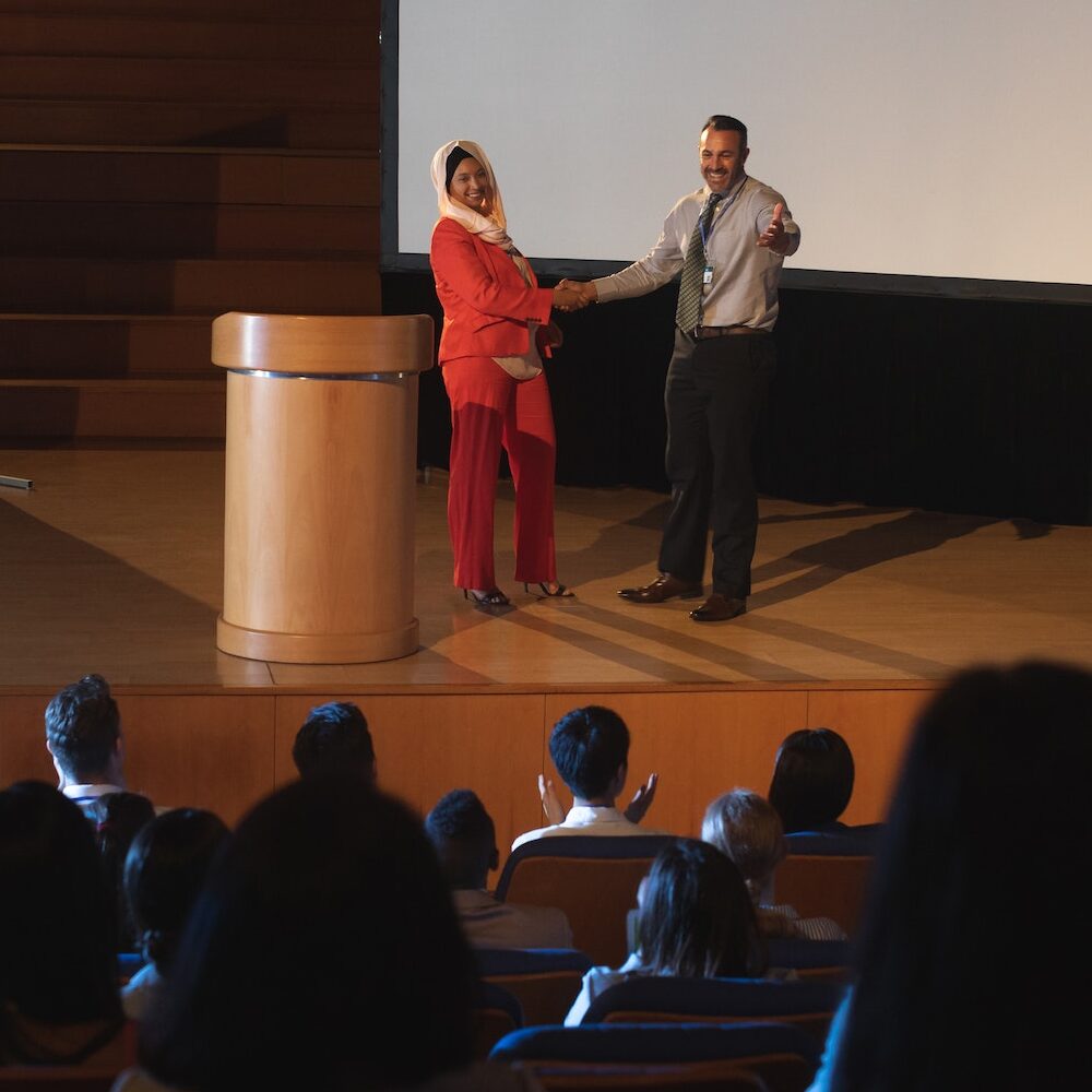 Business colleague discussing with each other in front of the audience while shaking hand